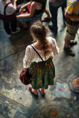 Obraz premium Young woman wearing a floral wreath enjoying Oktoberfest festival, surrounded by a lively crowd and festive decorations.