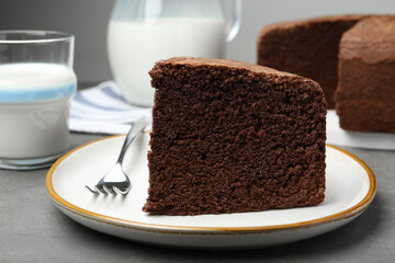 Piece of tasty chocolate sponge cake served on grey table, closeup