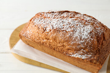 Tasty sponge cake with powdered sugar on white table, closeup
