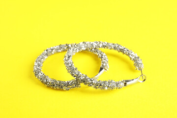 Beautiful bijouterie. Stylish earrings on yellow background, closeup