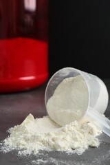 Protein powder in scoop on grey table, closeup