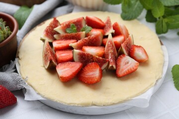 Making galette. Fresh dough, strawberries, figs and mint on light table, closeup