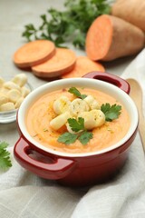 Delicious sweet potato soup with croutons and parsley on light table, closeup