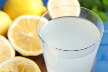 Fresh juice in glass and lemons on table, closeup