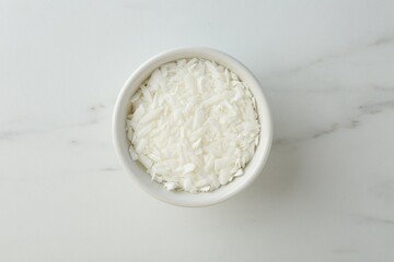 Soy wax in bowl on white marble table, top view