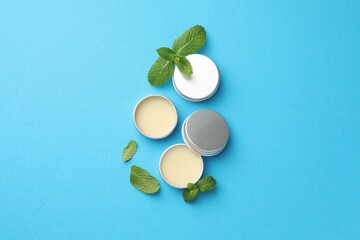 Natural lip balms and mint leaves on light blue background, flat lay