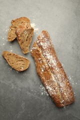 Cut fresh baguette on grey table, flat lay
