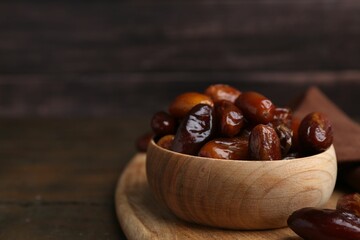 Tasty sweet dried dates in bowl on wooden table, closeup. Space for text