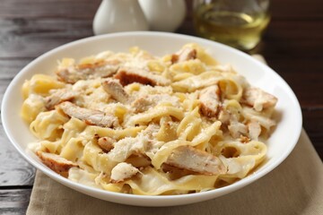 Tasty Alfredo pasta with chicken on wooden table, closeup