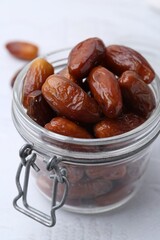 Tasty dried dates in jar on white table, closeup