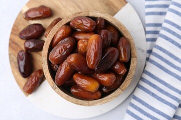 Tasty dried dates in wooden bowl on white table, top view