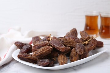 Tasty dried dates and tea on white marble table, closeup