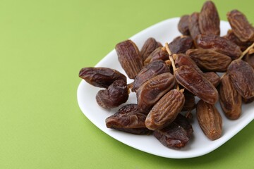 Tasty dried dates on green background, closeup. Space for text