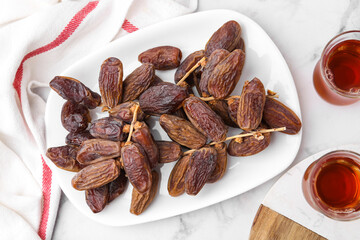 Tasty dried dates and tea on white marble table, flat lay