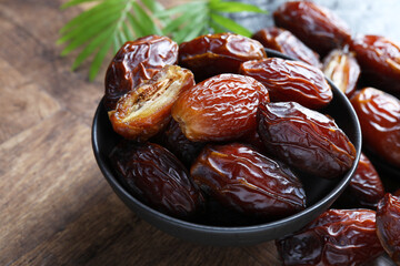 Tasty dried dates and leaves on wooden table, closeup
