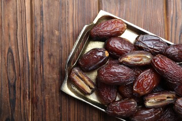 Many tasty dried dates on wooden table, top view. Space for text