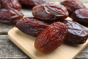Many tasty dried dates on wooden table, closeup