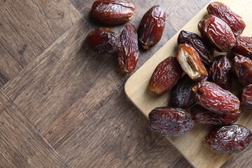 Many tasty dried dates on wooden table, top view. Space for text