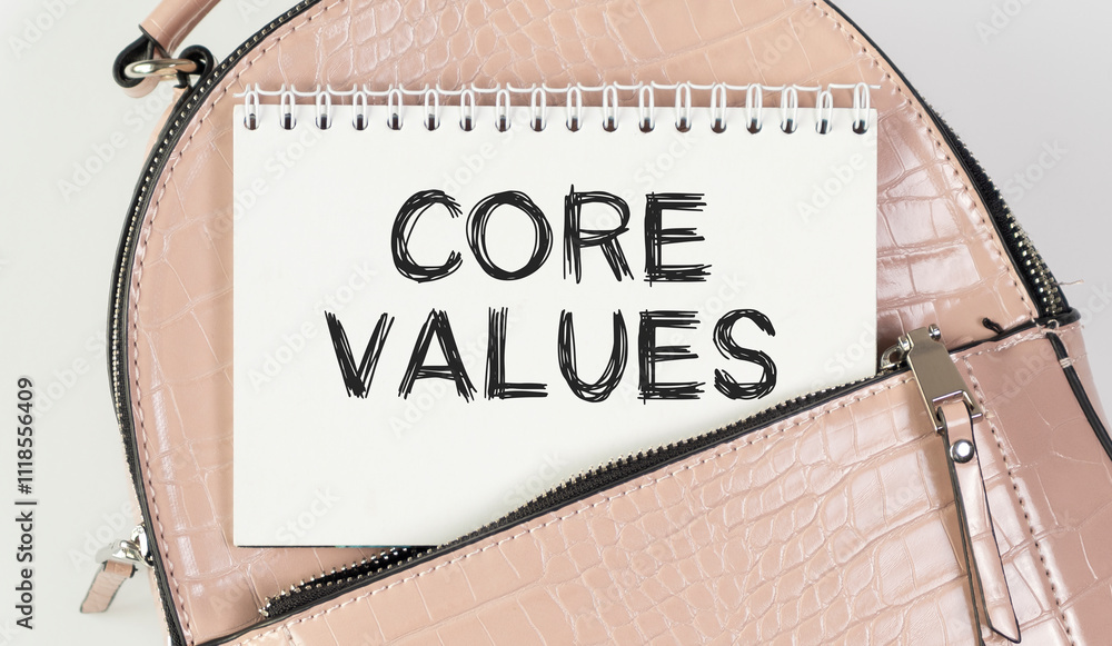 Poster notepad with text core values. a notebook peeks out of the pocket of a pink bag.