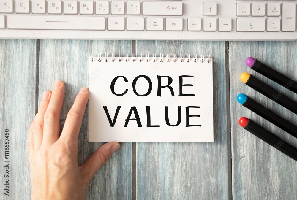 Poster notebook with text inside core values on table with coffee, laptop and some sheet of papers with cha