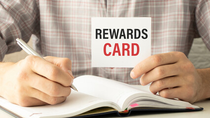 Businessman putting a card with text REWARDS CARD