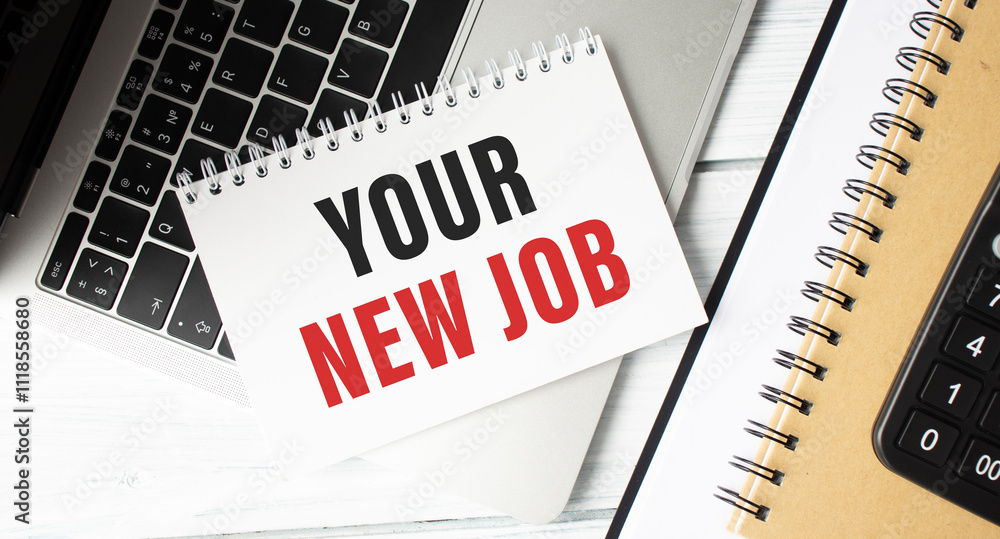 Poster notepad with your new job text on keyboard with felt-tip pens and calculator on wooden background.