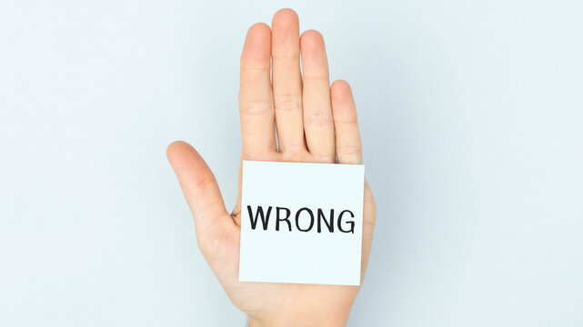 A business man holding a paper in front of his face with the text wrong