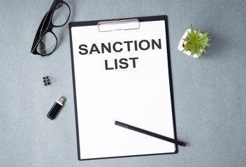 Sanctions list on a desk. Keyboard, glasses and book. Government act for sanctioned countries...