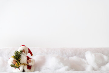 Santa Claus in red fur wading through deep snow to deliver Christmas presents with white background and room for copy