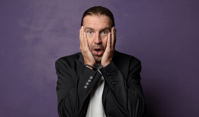 Obraz premium looking excited and surprised, open-mouthed with both hands on head, feeling like a lucky winner