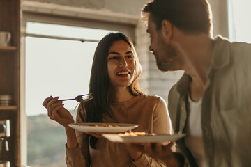A couple is eating spaghetti in a light-filled kitchen. Romantic lunch at home