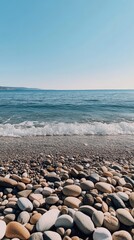 Coastal Serenity: A tranquil scene unfolds as the gentle waves of the sea caress a pebbled shoreline under a cloudless sky. This image evokes a sense of peace and the timeless beauty of the coast. 