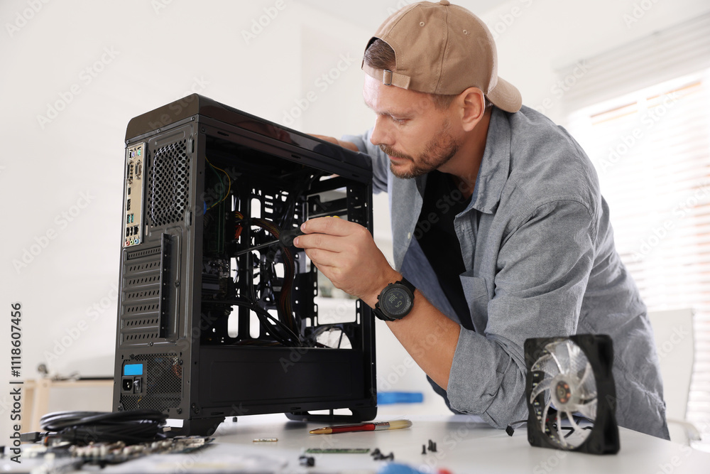 Poster man installing fan into computer at white table