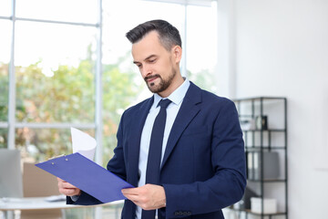 Handsome banker working with clipboard in office