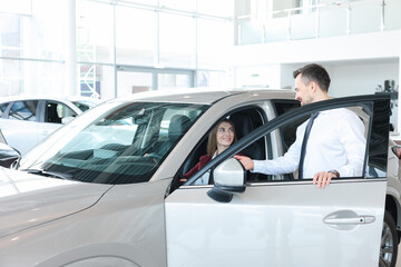 Happy salesman showing car to client in salon