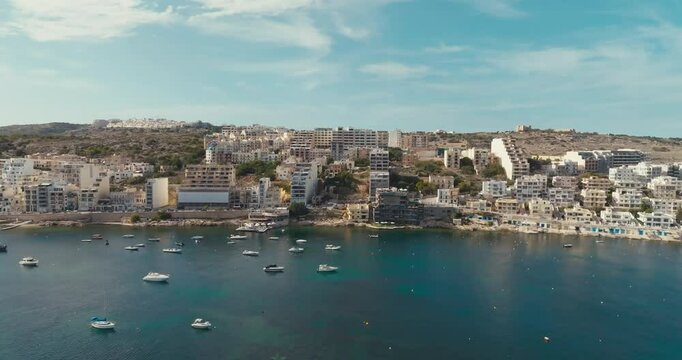 Bird Eye View of Bugibba Malta with Scenic Mediterranean Coastline Showing Urban Beaches Marina and Boats in a Beautiful Tourist Area. High quality 4k footage