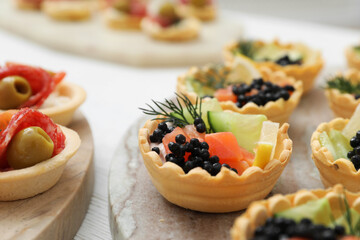 Many different tasty canapes on white wooden table, closeup