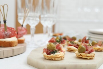 Many different tasty canapes on white wooden table, closeup