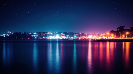 Vibrant city lights reflected on calm night water, with a starry sky.