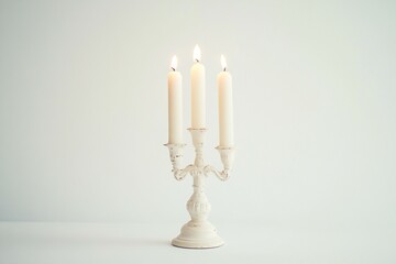 A white background features an antique candlestick adorned with white candles that have glowing flames.