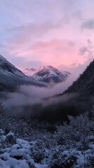 Obraz premium Pink Sky Mountain Peaks: A breathtaking view of snow-capped mountain peaks bathed in the soft glow of a pink sunrise, as mist swirls through the valleys. The scene evokes a sense of peace.