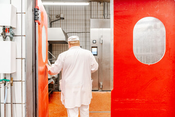 Butcher opening red door in food processing plant