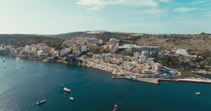 Aerial Drone View of Bugibba Malta Showcasing Coastal Cityscape with Tourist Beaches Marina Yachts and Mediterranean Waters. High quality 4k footage