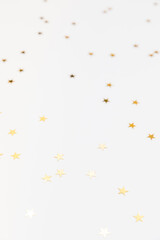 Gold sparkle confetti stars on a white background. Glitter, shine, bright. Christmas festive flat lay, winter holiday, new year, happy birthday concept. Banner for greeting card, top view, copy space.