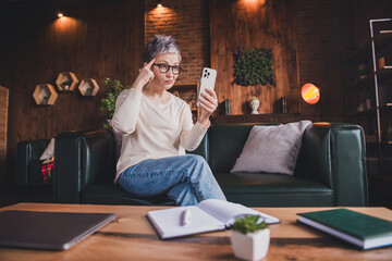 Charming mature woman with short grey hair wearing casual pullover, enjoying leisure time in daylight indoor