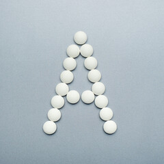 Letter a made of white pills on a grey background