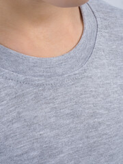 Gray t-shirt on a person. Simple gray t-shirt design. Close-up of gray t-shirt fabric. Minimalist gray t-shirt style.