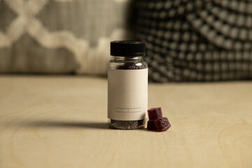 Plain empty blank sleep gummy bottle jar on rustic wood background with pillows