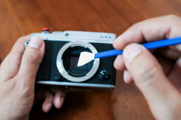 Cleaning the camera sensor with cleaning swab from dust and dirt on wooden table and. Cleaning and care of the camera sensor. The concept of care for professional photographic equipment.