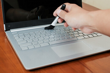 Close up of man hand cleaning dust from laptop keyboard using air pressure cleaner, Cleanliness concept.